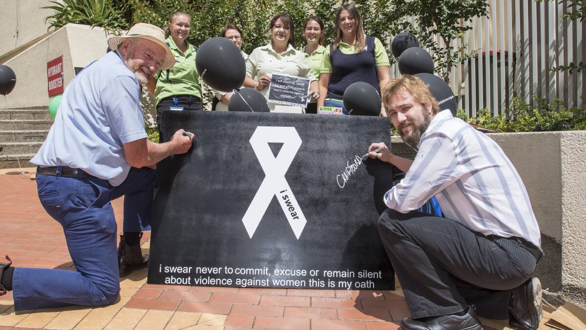 Signing on: Peter Price and Craig Foord sign pledge to not commit domestic violence. Photo: Peter Hardin 231118PHB003
