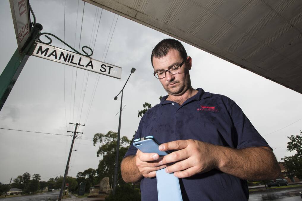 CALLING IN: Manilla's Hart Rural manager Jacob Hawley had to drive to Attunga just to retrieve messages on his mobile phone. The town's had numerous phone and internet blackouts, which have hurt businesses. Photo: Peter Hardin 