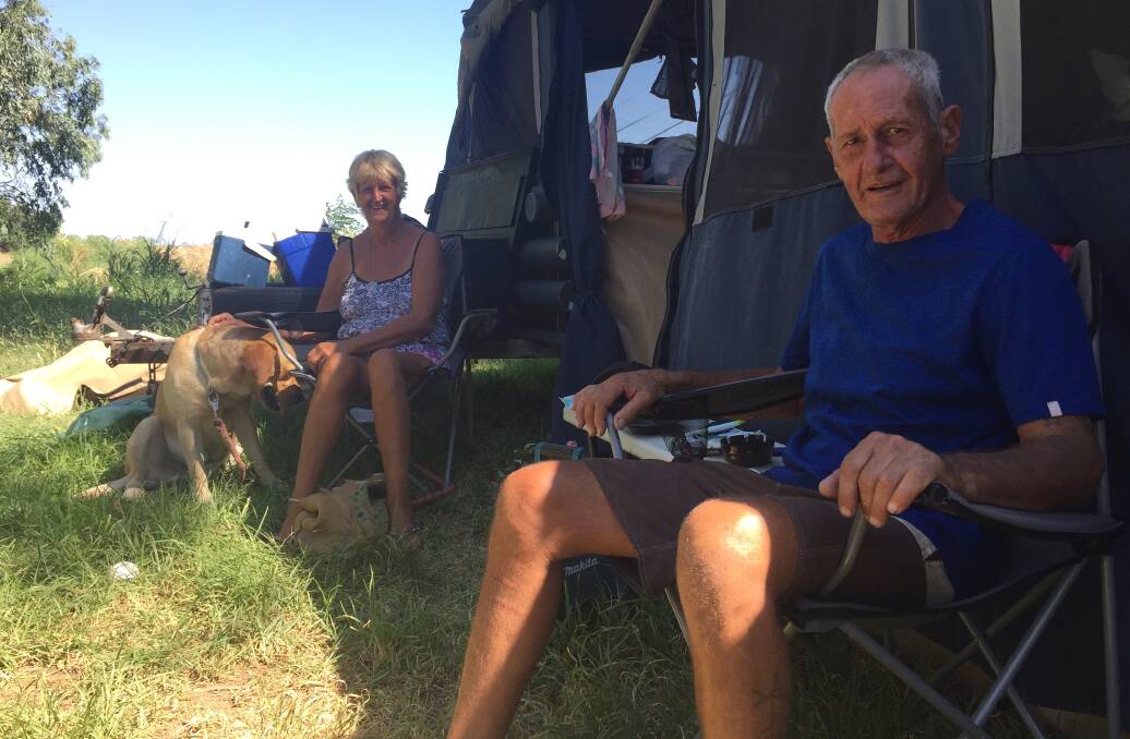 Taking shade: Leigh Hazell and Mick Abrahams, with golden labrador Elliot, take respite from the heat by the banks of the Namoi River in Gunnedah. Photo: Sam Woods