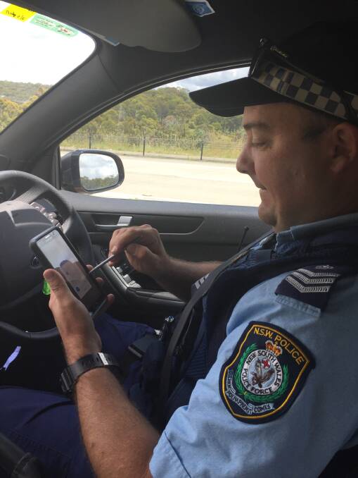 Instant ticket: Sergeant Michael Buko uses a MobiPOL to issue an infringement for a Glen Innes woman caught speeding on the New England Highway.