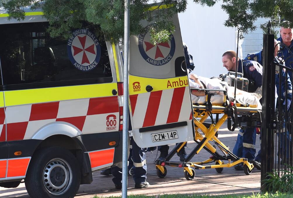 Ladder fall: Paramedics wheel the injured man into the back of the ambulance on Thursday afternoon. Photo: Gareth Gardner