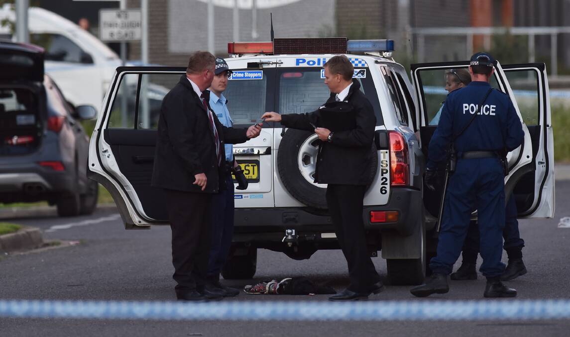 Crime scene: Aubrey Michael Flick is placed in the back of a police car while detectives stand guard in Tamworth, last year. Photo: Gareth Gardner