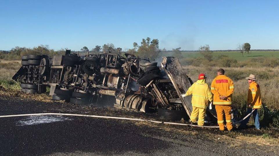 WRECKAGE: Fire crews work to hose down the smouldering truck following the head-on collision just north of Gurley, early on Saturday morning. Photo: Live Traffic NSW