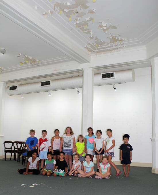 Students participating in Moree Plains Gallery's holiday art classes show off the extent of the peeling paint from the ceiling. The students are excited to see the ceiling receive a fresh coat of paint this week, but would love the community to help fund the repairs to allow programs such as the holiday art classes to continue.