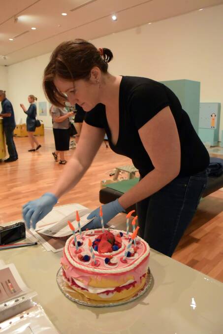 FINE-TOOTH COMB: National Museum of Australian objects conservator Natalie Ison checks every pom pom and button on this crafty birthday cake that's part of the exhibition. 
