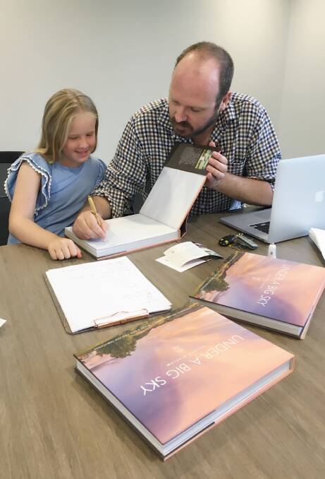 LAUNCH: Anna Pollard, 9, watches Andrew Pearson sign his book for her mum Joanne Stead's birthday. Photo: Carolyn Millet 110217CMA01