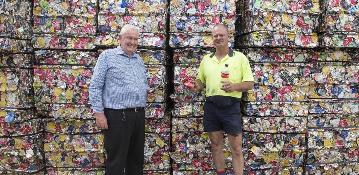 Canned coin: Challenge's Barry Murphy and Victor Collett stand in front of some of the 6 million containers recycled at the Tamworth plant each year. From Friday the organisation will earn 10 cents for each container. Photo: Peter Hardin