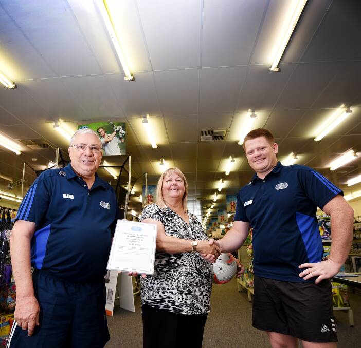 Shake hands with the ref: Sportsmans Warehouse managers Bob Barber and Ricky Craig congratulate local Lyn O'Brien who celebrated fifty years with a whistle this year on the netball courts. Photo: Gareth Gardner 071216GGA02