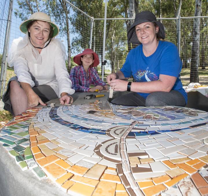 COLOUR KALEIDOSCOPE: Emma Stilts, Emma Trigg and Karen Balsar are on track to completing the mosaic seat that represents the Peel River in Bicentennial Park. Photo: Peter Hardin 261116PHA007
