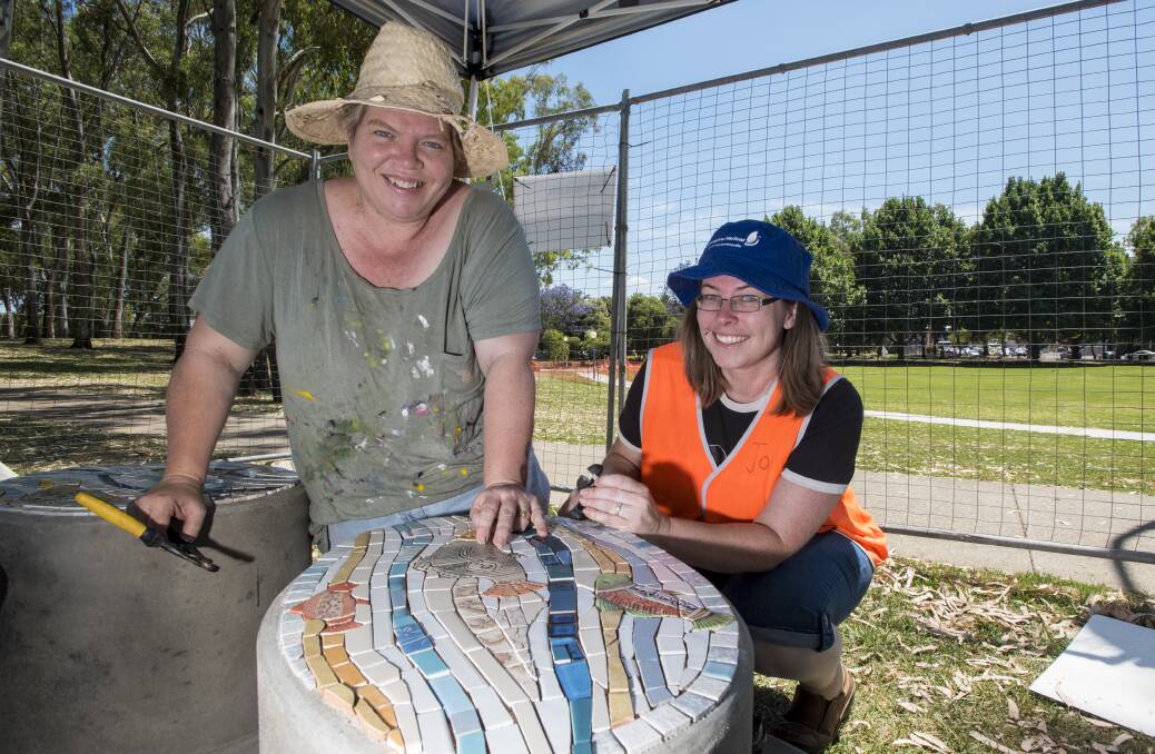 WORK OF ART: Jodie Herden and Joanne Stead help launch The Changing Face of the Peel by completing a mosaic seat. Photo: Peter Hardin 261116PHA016