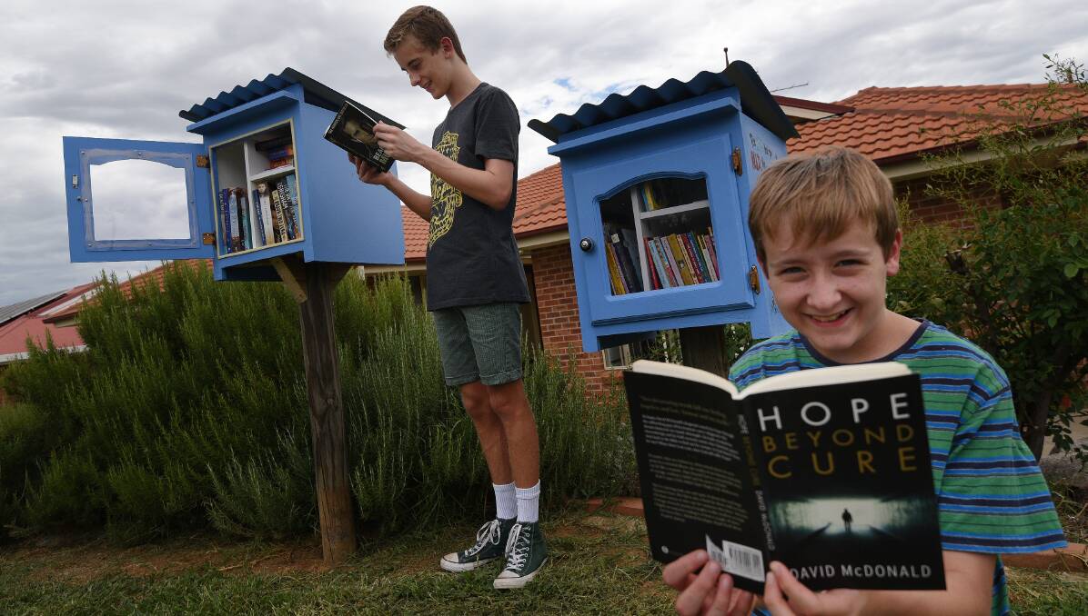 BROTHERS AND BOOKS: Josh, 14, and Nathan Carter, 12, test out their mum's new book boxes in Oxley Vale. Photo: Gareth Gardner 311216GGC03