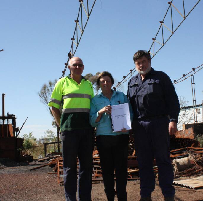 David (left) and Linda Campbell with Dan Sanderson and a copy of their report in the shearing shed the Campbells lost in last year's fires.