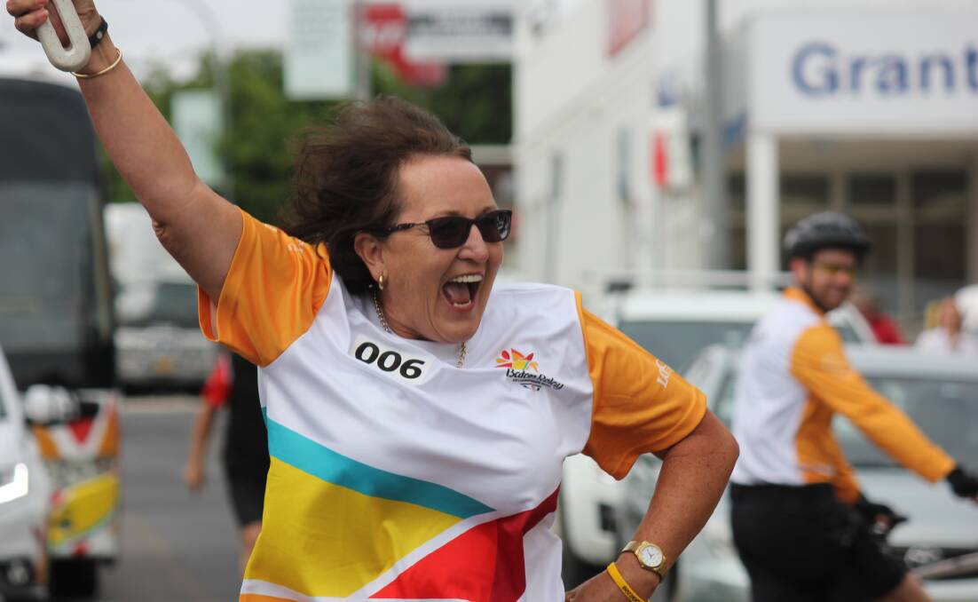ALL SMILES: Queen's Baton Relay baton bearer Julie Gates jumps for joy as she carries a message from The Queen through the streets of Armidale.