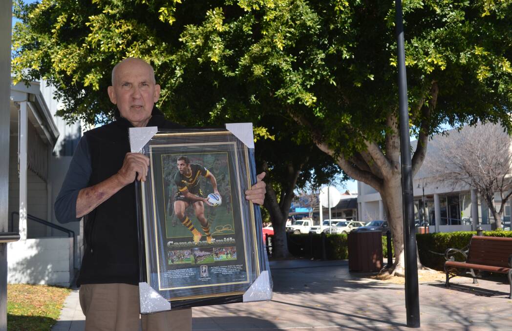 GOOD CAUSE: Men of league's Tony Woodham carries one of the five framed prints to be auctioned in Moree on Sunday.