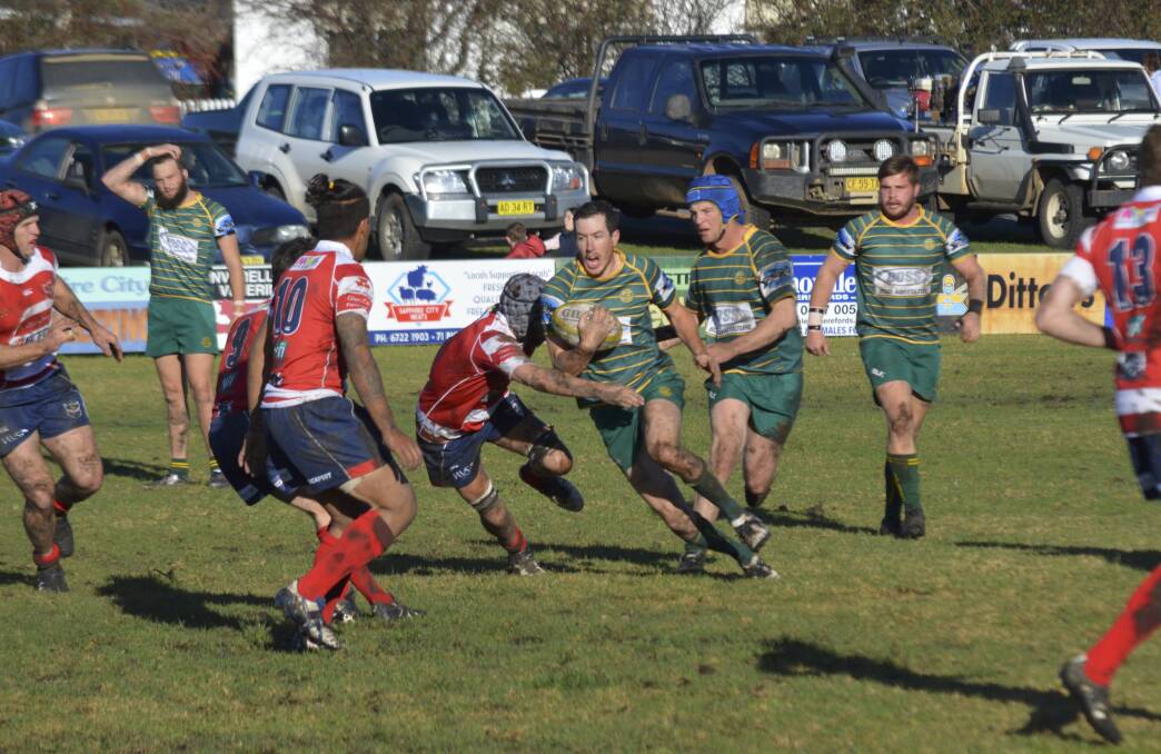 Fun in the mud: Inverell's Nathan Worgan spots a little gap in the Walcha defensive line but the Rams' players converge to shut it down. Photo: Inverell Times