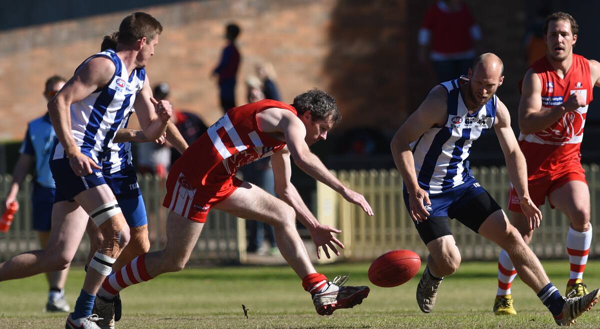 On the ball: Swan Stephen Fairless reaches for the loose ball as Roos stalwart Daniel Johnson and  Luke Robinson (left) converge.