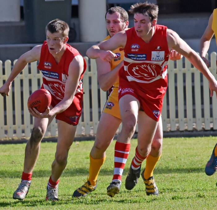 Let's get out of here:Julian Jasper handballs the Swans out of trouble as teammate Sam Burges runs interfernece on Suns' Dom Brown during the Swans' win on Saturday. Photo: Geoff O'Neill. 230716GOC07.
