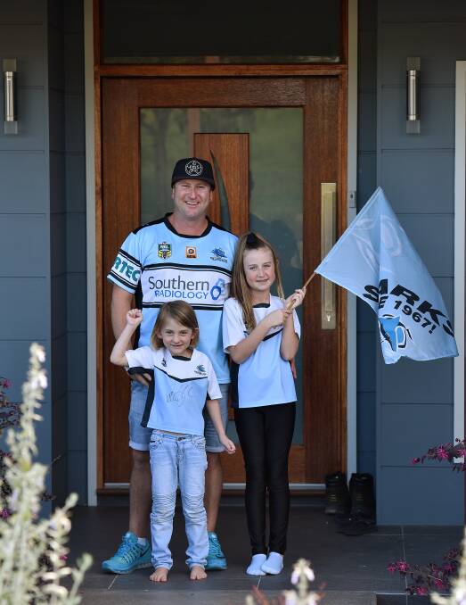 SHARK FAMILY: From left: Eva, 5, Portia, 11, in front of dad Steve McGarrity who's on his way to see his beloved Sharks in the NRL grand final. Photo: Gareth Gardner 260916GGE01