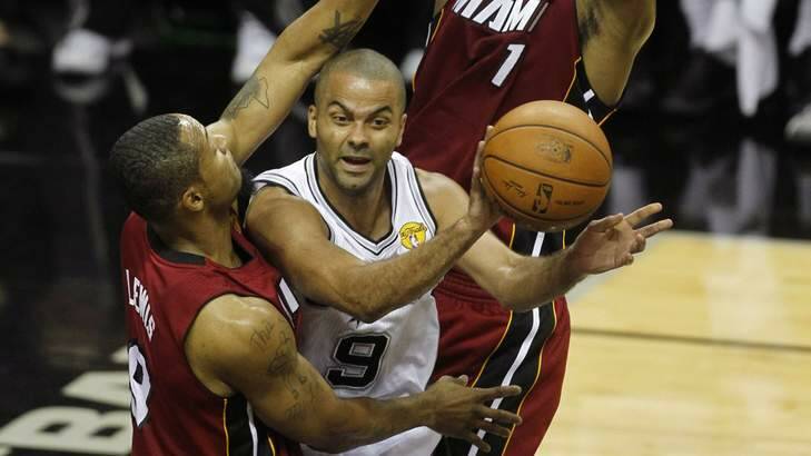 San Antonio Spurs guard Tony Parker passes as he is defended under the basket by Miami Heat's Rashard Lewis and Chris Bosh during the first quarter in Game 1 of their NBA Finals series in San Antonio. Photo: Reuters