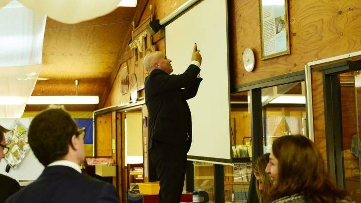 Adrian Piccoli photographs a story on a library wall about David Gonski's visit to Villawood North Public School. The issue of Gonski funding is on the education agenda. Photo: Nick Moir