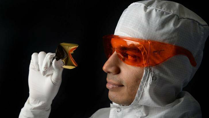 Associate Professor Sharath Sriram, pictured with an optical chip, must wear a protective suit when working in the lab. Photo: RMIT