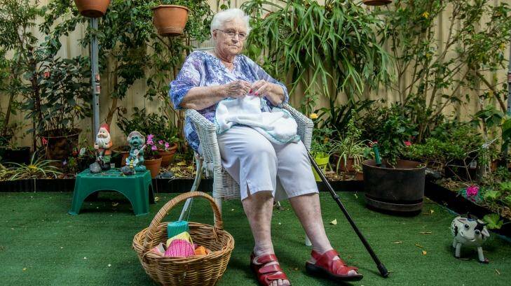 Margaret McClune, 85, knits in the backyard of her assisted living home by the fence that will be just metres from a new pub development next door in Casula, Sydney. Photo: Cole Bennetts