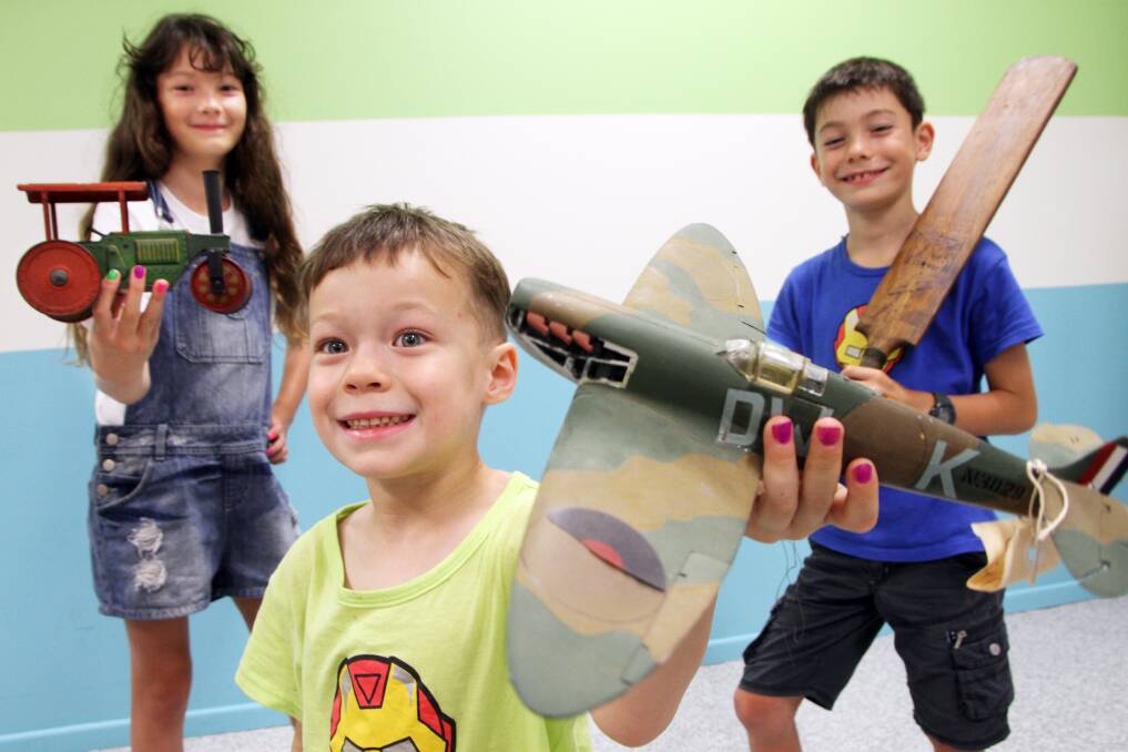 Siblings Sienna, 10, Julian, 5, and Finlay Wu, 8, of Canberra, enjoyed trying out some of the historic toys at Redland Musuem during a summer visit with their Cleveland grandparents. Photo by Chris McCormack