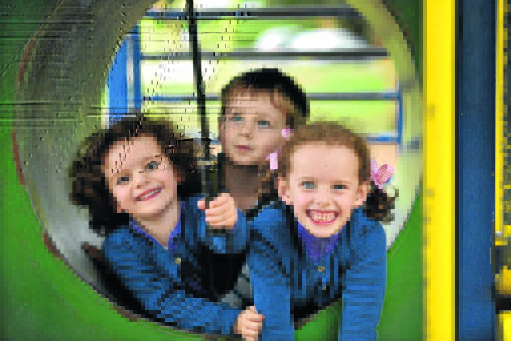 KIDS PLAY: A little bit of rain didn t stop Louisa Foreman, 4, Finn Hagley, 2, and Gabriella Foreman, 6, from having some sunny smiles during play at Anzac Park yesterday. 
Photo: Geoff O Neill 010515GOC03