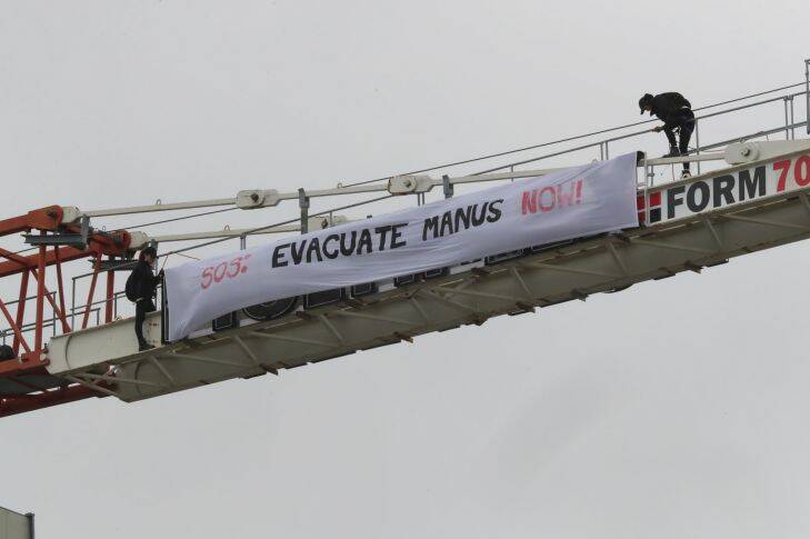 Protesters climb a crane to display a banner regarding refugees on Manus Island during the 2017 Melbourne Cup Day at Flemington racecourse in Melbourne, Tuesday, November 7, 2017. (AAP Image/David Crosling) NO ARCHIVING