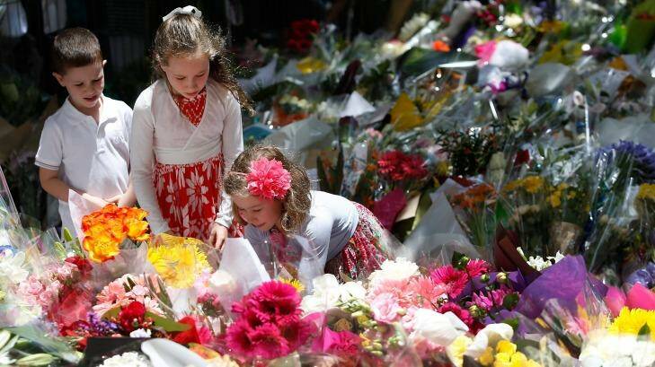 Sea of blooms: A girl adds flowers to the tributes at Martin Place. Photo: Daniel Munoz