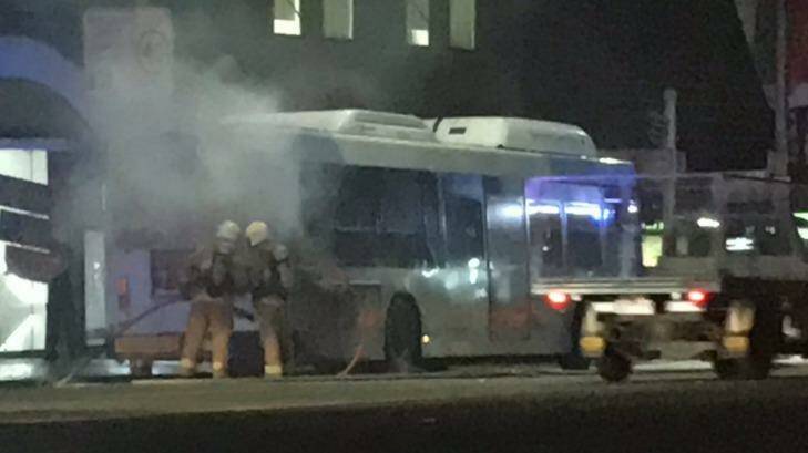 Firefighters extinguish a fire on a bus in George Street, Sydney, on Thursday night. Photo: Jim Cook