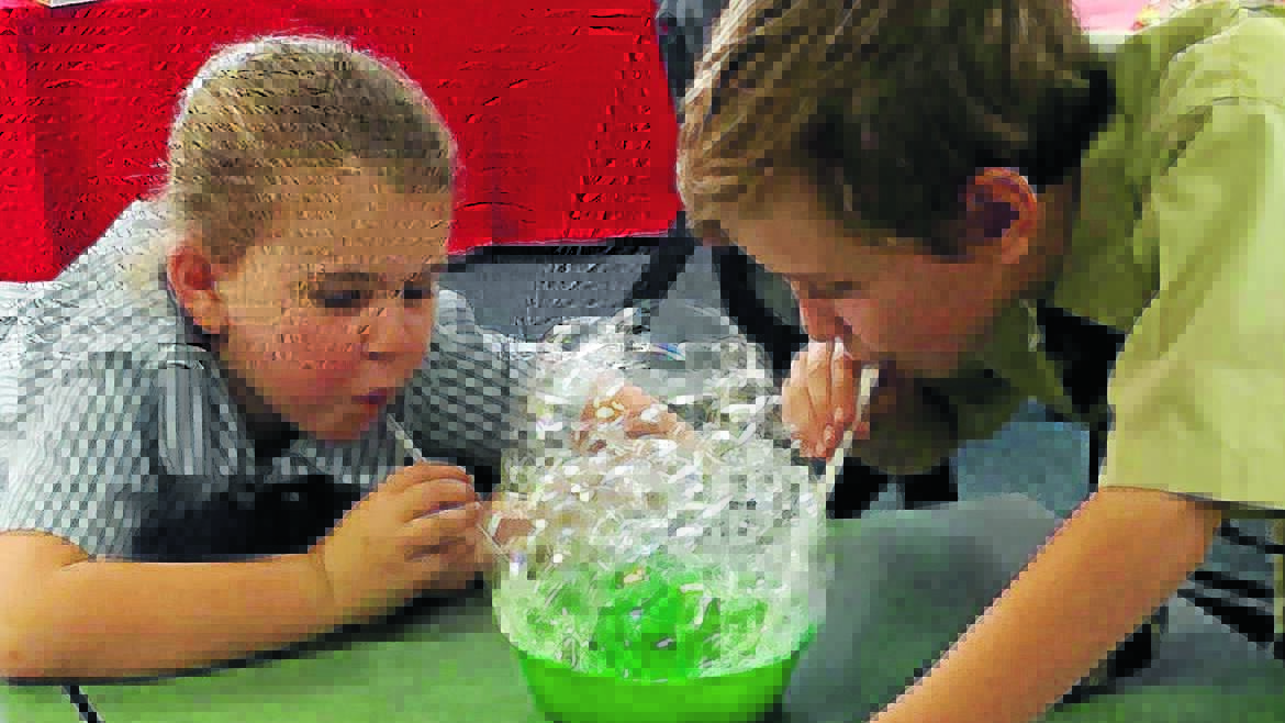 Ava Watts and Mitchell Evans learn about surface tension as they blow bubbles.