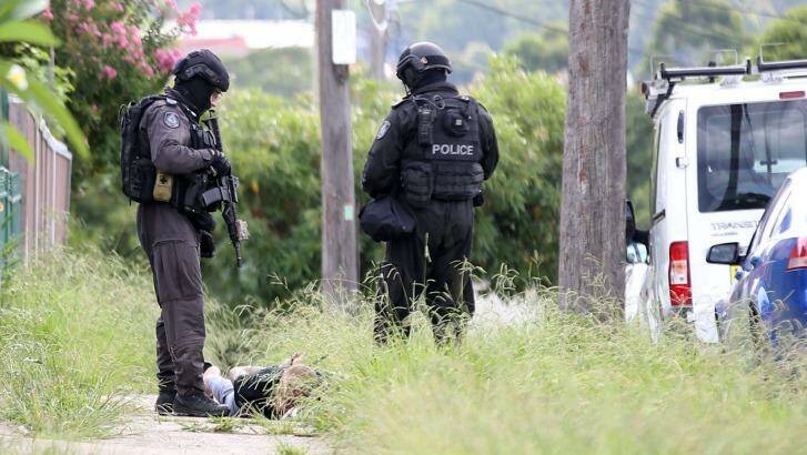 Police watch over Ahmad Abdullah as he lays face down on the ground in handcuffs. Photo: James Alcock