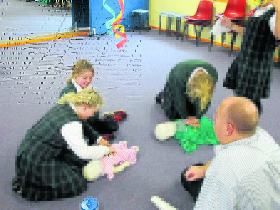 Hanna Collins and Lydia Aulton perform CPR on and infant and adult under the supervision of Jamie Day
