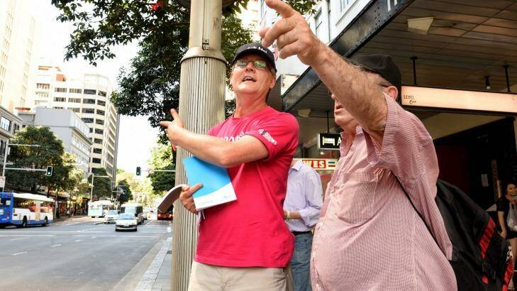 Sydney bus street team member Julian Buckell helps commuters in Park Street on Monday.  Photo: Steven Siewert