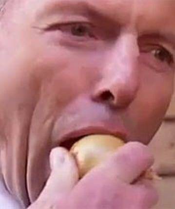 Tony Abbott bites into a raw onion