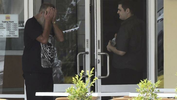 Fatal shooting: A man with his head in his hands at Hungry Jack's, Hoxton Park. Photo: Brendan Esposito