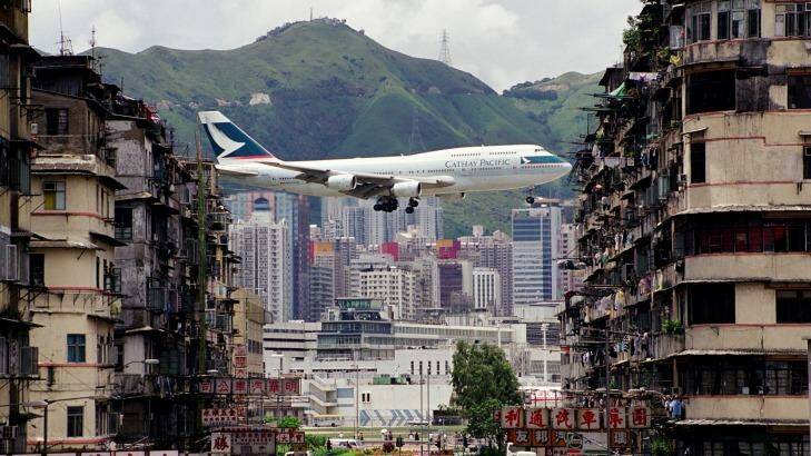 A Cathay Pacific jumbo jet flight heads in for a landing at the old Hong Kong Airport, a famously spectacular path that flew between apartment blocks.
