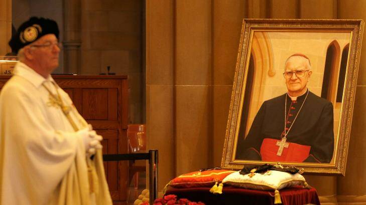 A priest stands close to a portrait of Cardinal Edward Clancy. Photo: Daniel Munoz
