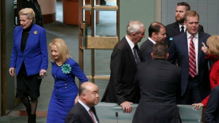 Former speaker Bronwyn Bishop enters the chamber while Tony Smith is congratulated by colleagues in the House of Representatives following his selection as her replacement. Photo: Alex Ellinghausen