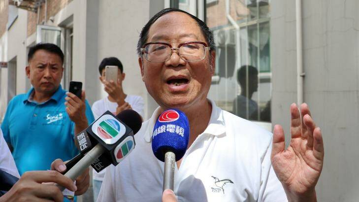 Hu Dehua, the deputy publisher of <i>Yanhuang Chunqiu</i> and the son of late liberal Chinese leader Hu Yaobang, speaks to media in front of the journal's office in Beijing, while unidentified plain-clothes men watch and film proceedings. Photo: Sanghee Liu