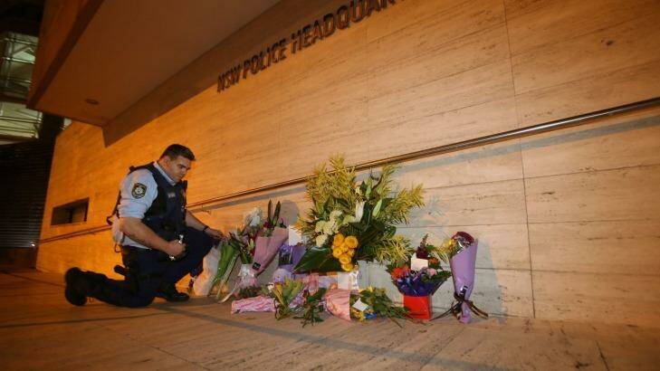 A police officer arranges flowersoutside the Parramatta HQ. Photo: James Alcock