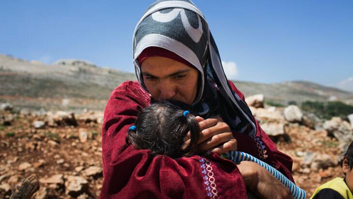 Syrian woman Lina kisses her two-year-old daughter outside her makeshift tent in Lebanon. Photo: Andrew McConnell