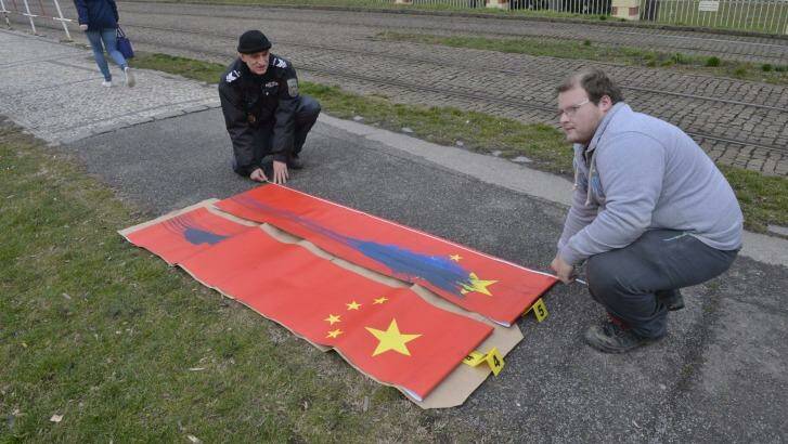 Policemen inspect Chinese flags defaced near Prague Castle on Saturday, ahead of the visit of Chinese President Xi Jinping. Photo: CTK via AP