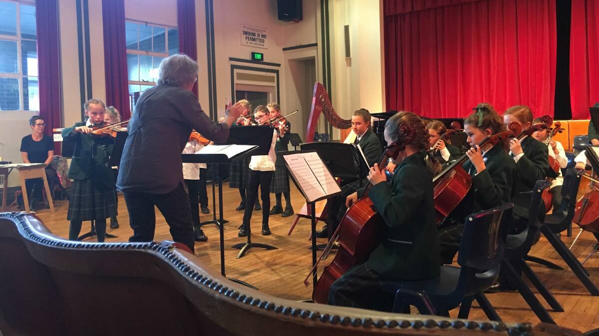 PLC Armidale Junior strings performing at the eisteddfod with conductor, Mrs Deidre Rickards at the Old Armidale Teacher's College Auditorium