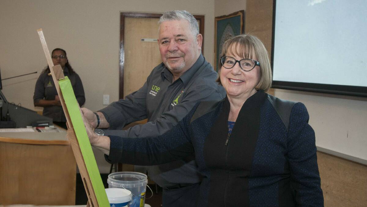 Gregory Davison and UNE vice-chancellor Annabelle Duncan place their hand prints on canvas for Sorry Day
