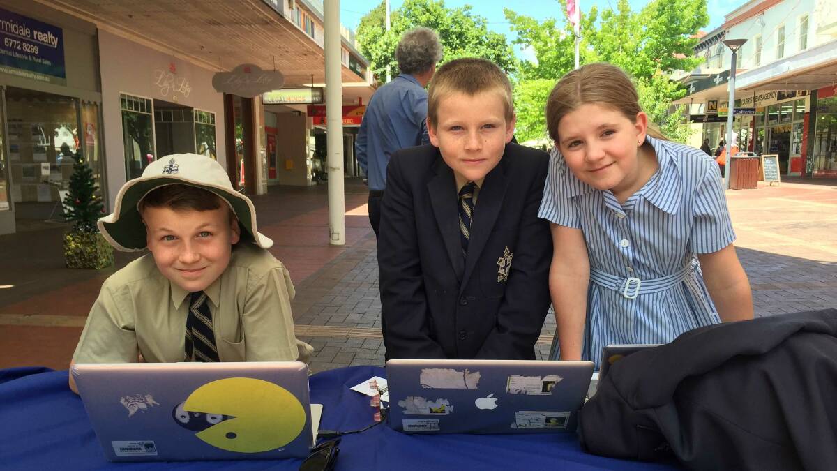 Junior school students Marcus Hempel, Harrison Price and Ruby Straker show off their technological know-how at the pop-up IT stand in the Armidale mall