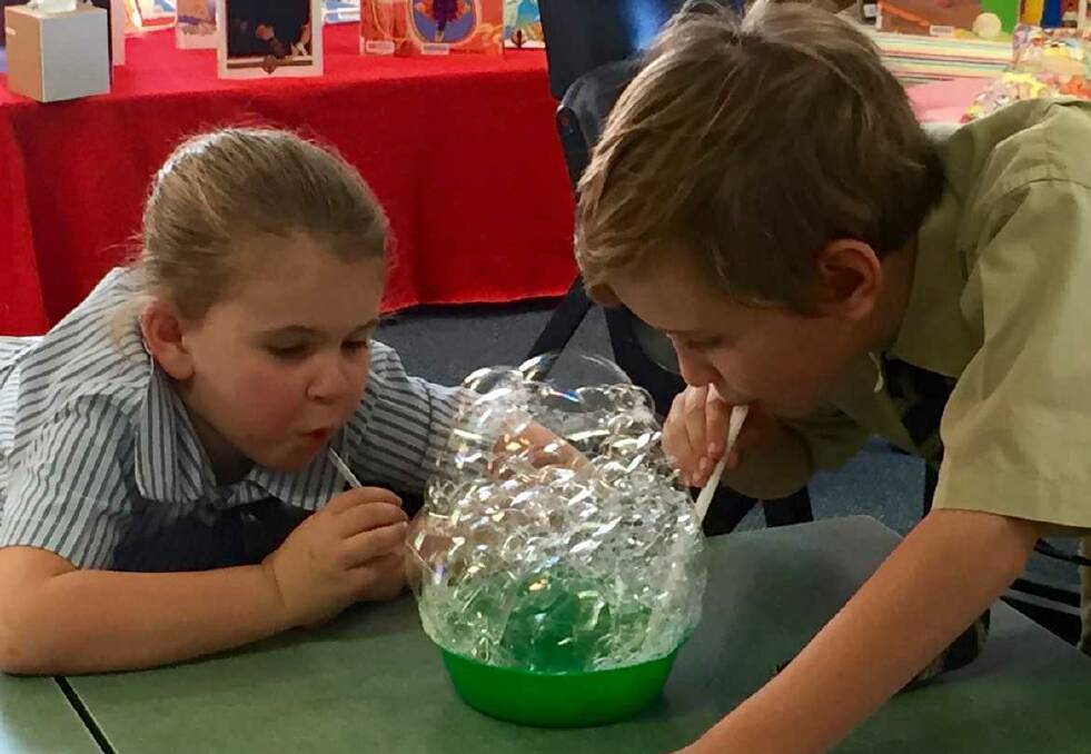 Ava Watts and Mitchell Evans learn about surface tension as they blow bubbles
