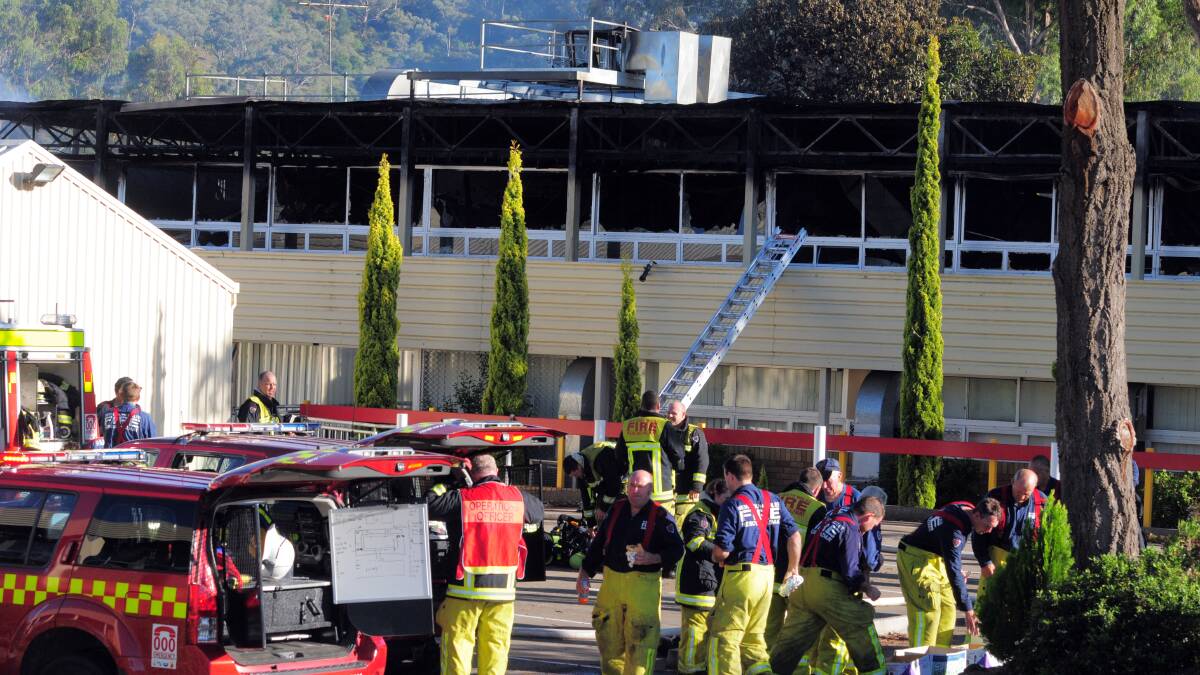 ARSON ARREST: The morning after the suspicious blaze, firefighters were still at the scene of the Oxley High School fire mopping up.