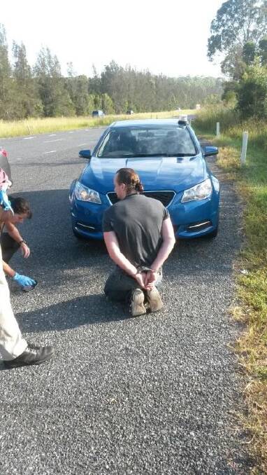 UNDER ARREST: Daniel Gallaher was handcuffed on the side of the Pacific Highway and has been charged in relation to an Armidale drug ring which uncovered drugs and replica pistols during raids this week. Photo: NSW Police